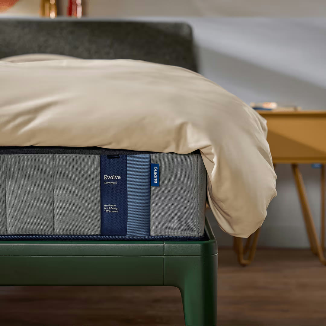 Auping Evolve matras opgemaakt op een groen bedframe